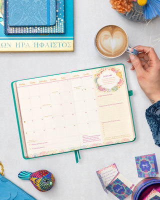 Monthly planner spread from Intrinsic 'Year to Ignite Your Light' Diary in aqua green, featuring calendar, goal-setting, gratitude practice & motivational quotes by Adèle Basheer.
