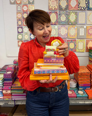 Adèle Basheer with a Yellow Lovers Mystery Bundle from the Intrinsic Archive Sale, featuring vintage gems, display samples, and end-of-line pieces from past journals, stationery, travel, ceramic, jewellery, accessories or homewares collections.