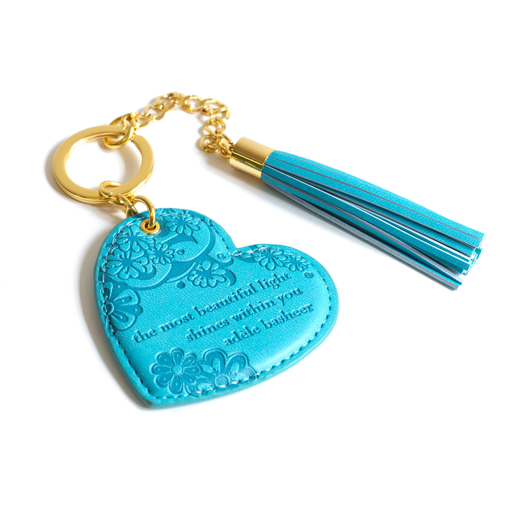 Inspirational vegan leather heart shaped light blue keychain with gold chain and bright blue tassel. Designed in South Australia. Motivational quote by Adèle Basheer.