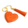 Inspirational vegan leather heart shaped orange keychain with gold chain and bright orange tassel. Designed in South Australia. Motivational quote by Adèle Basheer.